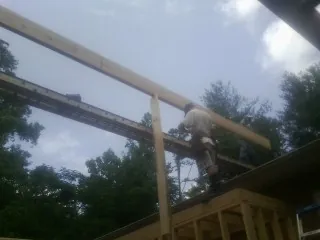 Carpenter setting a ridge beam over a new addition frame — Ice Dam Removal by Roofing Brothers in Milton Mills