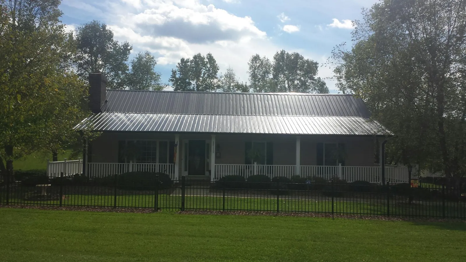 Gray metal roof on a brick ranch with a full width front porch — Gutter Guard Installation work by our crew in Milton Mills