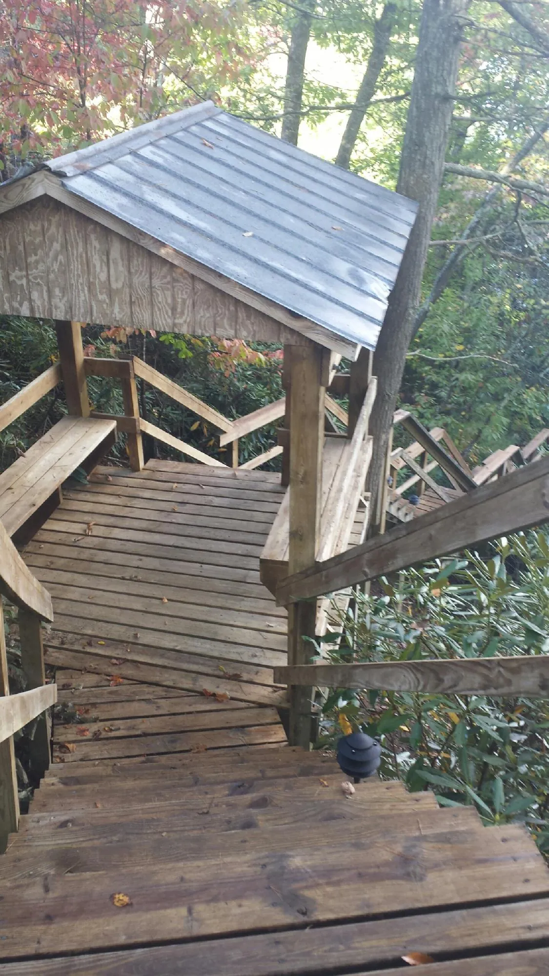 Metal roofed shelter over wooden steps on a wooded walkway — Skylight Repair & Installation work by our crew in Milton Mills