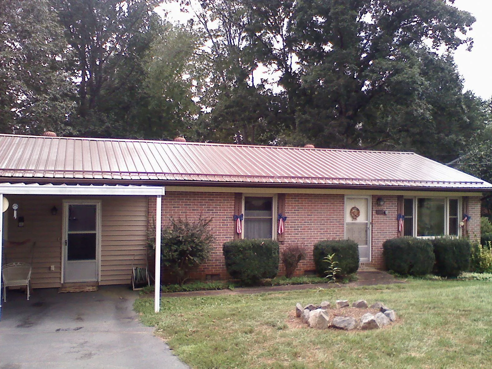 Bronze metal roof and carport on a brick ranch home — Roof Repair work by our crew in Milton Mills