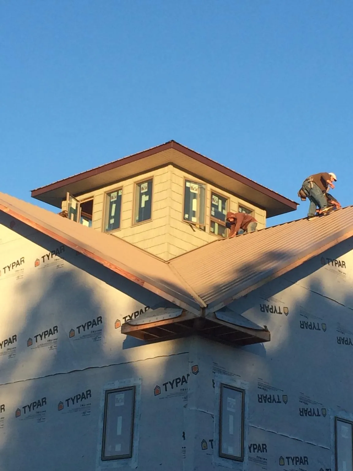 Roofers working around a rooftop cupola on a new metal roof at sunset — Roof Waterproofing in Milton Mills by Roofing Brothers